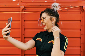 young model with alternative look taking selfie and laughing - lifestyle concept