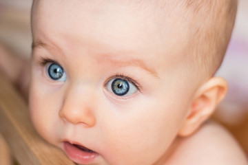 Amazed baby looks in surprise, big open eyes, close up