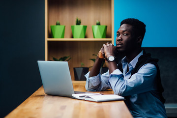 Freelance concept. Man in casual clothes  is examining documents and smiling while working with a laptop in kitchen. Working at home.