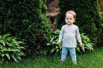 Beautiful little girl with flower on her head outdoors in sunny day. 2 years girl.