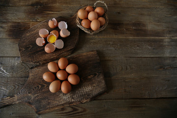 Fototapeta na wymiar organic raw chicken eggs in a basket, egg shells and egg yolk on a wooden rustic board. Healthy eating concept. Easter. Flat lay, top view, with copy space for text and image.