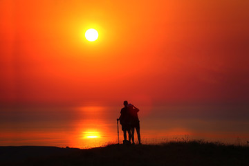Fototapeta na wymiar Travelers together at sunrise stand by the sea
