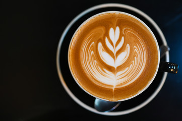 Latte art coffee in black cup on  black table, Dark tone