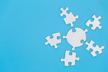 Unfinished white jigsaw puzzle on blue background with copy space. Business strategy teamwork and problem solving concept.