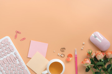 Flat lay women workspace - keyboard, mouse, cup of tea, rose flowers, jewelry and stationery on a pink pastel background. Feminine office table desk frame. Top view,copy space,
