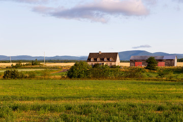  Pretty horizontal view of a stone house and wooden barn in Saint-François village during a summer sunrise, Island of Orleans, Quebec, Canada
