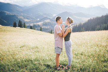 Lifestyle loving couple hugging at nature among mountains in summer.