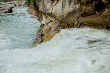 Stones and mountain river with small waterfall, blurred background, the flow of a mountain river