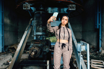 Fototapeta na wymiar Beautiful young stylish girl posing at abandoned factory outdoor with an old broken engine.