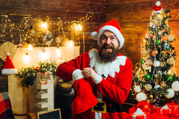 Christmas stockings. Styling Santa hipster with a long beard posing on the Christmas wooden background. Winter emotion.