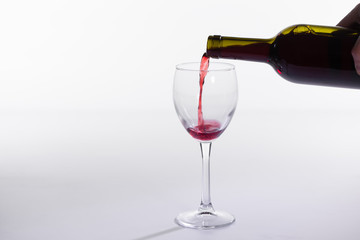 Pouring red wine into the glass on white background with copy space