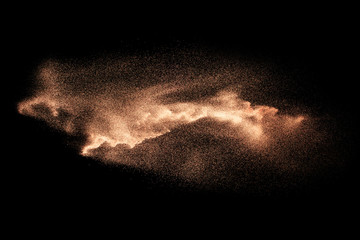 Fototapeta na wymiar Abstract sand cloud.Brown sand splash against dark background. Brown dust explosion.