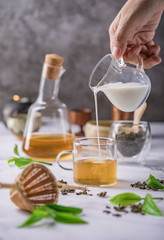 Hot tea in glass teapot and cup with steam on dark background.