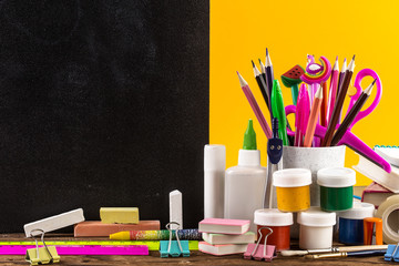 Stationery on a table in front of blackboard