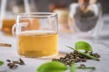 Hot tea in glass teapot and cup with steam on dark background.