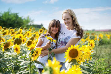 Carefree daughter enjoying with her mother among sunflowers