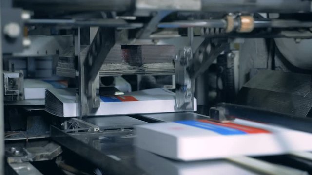 Typographic machine presses books on a conveyor.