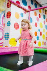 Fototapeta na wymiar A little baby girl 1-2 years playing and jumping on a trampoline in a children's playroom for her birthday. entertainment centre.