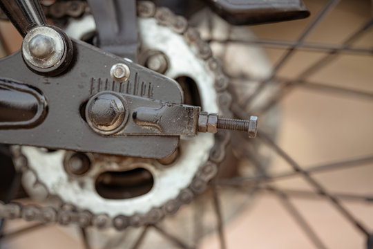 Closeup image of the mechanical parts of a bikes rear gear cog system with the chain in a used condition and the spokes of the frame and the visible in this cycling image