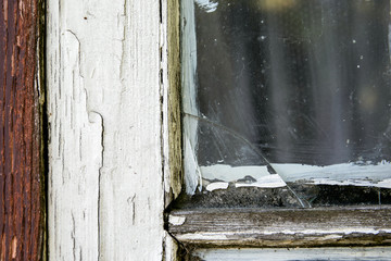 Old window pane with peeled of white color, crack in the glass