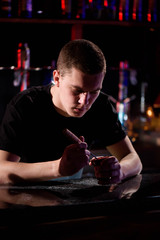 Barman fills black burnt ceramic bowl for hookah smoking different types of tobacco.