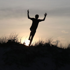 Silhouette Jumping off Sand Dune at Sunset