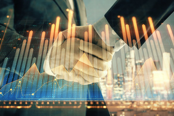 Double exposure of financial chart on cityscape background with two businessmen handshake. Concept of financial analysis and investment opportunities