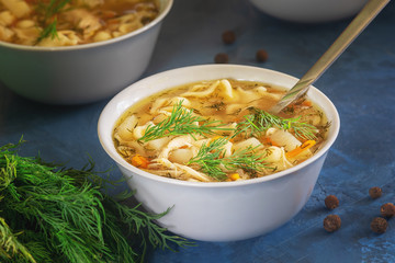 Chicken Noodle Soup Bowl Closeup Homemade Dinner. Healthy Starter Meal in White Dish with Spoon. Vegetable Poultry Bouillon with Cuted Potato and Dill Branch. Warm Pepper Seasoning Lunch