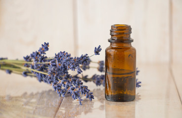 Lavender essential oil and dry lavender flowers on a wooden table