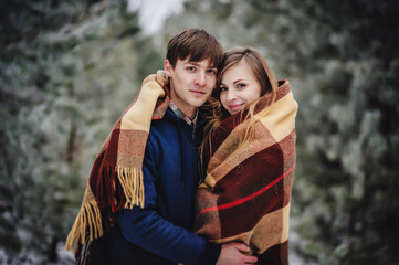 People, season, love and leisure concept - happy young couple hugging and laughing outdoors in winter. Man and woman walk in snow park.