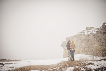 Lovely couple in the winter field on a walk with the dog. Dog walking with owner outdoor snowy nature.