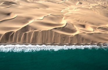Aerial view of Skeleton coast sand dunes meeting the waves of Atlanic ocean. Skeleton coast,...