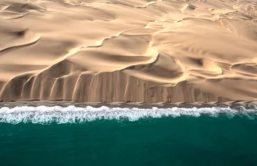 Foto op Plexiglas Aerial view of Skeleton coast sand dunes meeting the waves of Atlanic ocean. Skeleton coast, Namibia. © Kertu