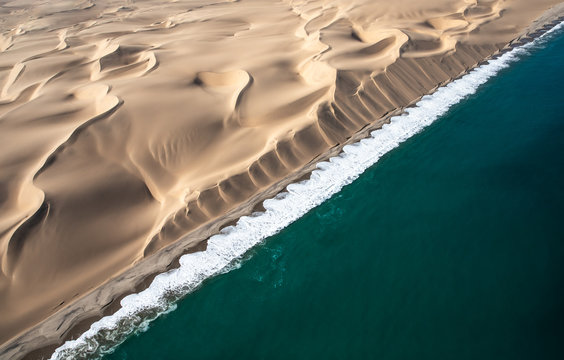Aerial view of Skeleton coast sand dunes meeting the waves of Atlanic ocean. Skeleton coast, Namibia.
