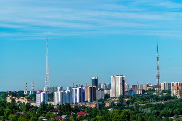 Before us is the area of the City Hills of Perm. On the hill there are high-rise and one-storey houses, television towers, many trees. Summer, June, early morning.