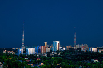 Fototapeta premium In the rays of the sun setting close-up one of the Central regions of Perm. High-rise buildings and TV towers are illuminated by the last rays of the sun. Summer, July.