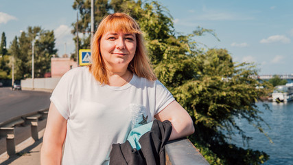 Portrait of a beautiful smiling woman is standing on the waterfront near the water.