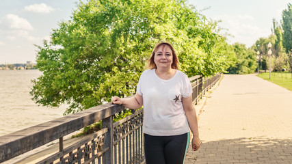 Portrait of a beautiful smiling woman is standing on the waterfront near the water.