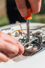 Repair and maintenance of the water heater. A man twists a screwdriver element of the water heater. Vertical orientation