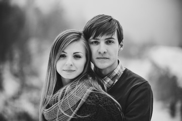 A romantic love couple walks in the snow park. Happy winter holidays. Black and white photo.