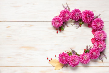  Floral decoration. with Pink Dahlijas, autumn leaves and cowberry. Concept for harvest festival, Lammas. Top view, close up on white wooden background.