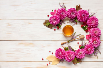  Floral decoration. with Pink Dahlijas, autumn leaves, cowberry and honey Concept for Rosh Hashanah the Jewish New Year, harvest festival, Lammas. Top view, close up on white wooden background.