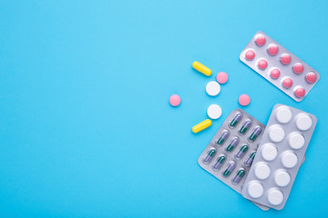 Colored pills and tablets in blister on a blue background, top view