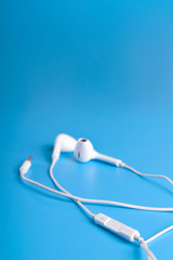 Mobile headphones of white color on a blue background in light colors with a place for text , copyspace. Top view.