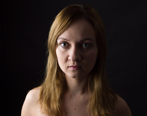 Naklejka premium portrait of young woman, no make up, low key, brown dark hair, natural looking making expressions 