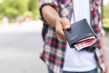 Hand of Asian tourist giving banknote and black wallet that he found in tourist attraction.