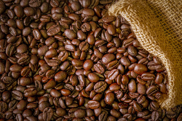 Coffee beans in a sack on dark brown background.