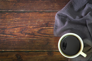 Cup of black coffee  and napkin on old kitchen wooden table. Top view with copy space