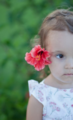 Little child girl with red flower behind her ear