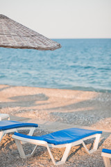 Obraz premium Sunbeds and umbrella on the beach by the sea. Beautiful concept for vacation, summer holidays and travel